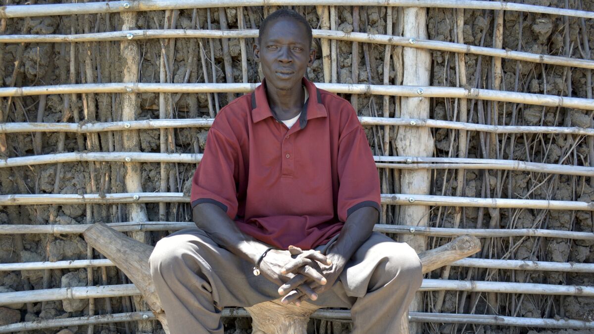 Luko Loku, a South Sudanese cattle herder from the Mundari tribe, sits outside his one-room thatched home.