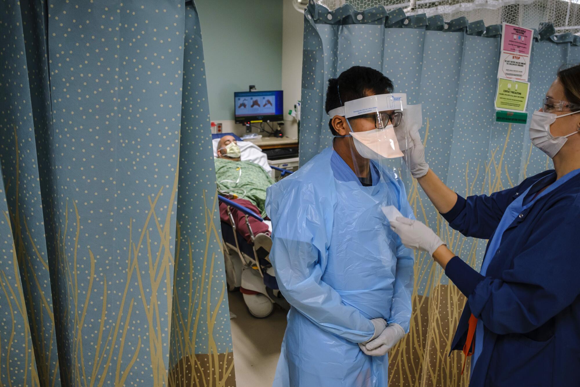 Nurse Arnold Garcia, center, gets help from a colleague disinfecting his gear.