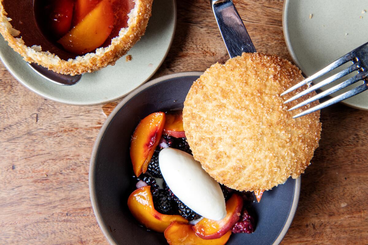 Closeup of fruit in a bowl with a dollop of creme fraiche and a biscuit top. 