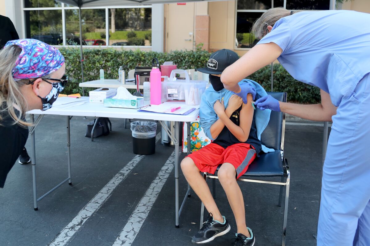Zach Murillo, 11, gets a flu shot from Kristen Goode, a BSN, RN, right, as his mother Allison looks on at Coastal Kids.