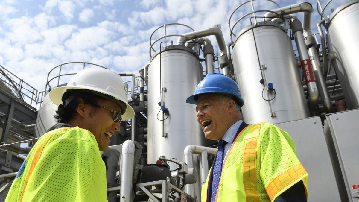 Inslee, right, visits a wastewater treatment plant in Washington.