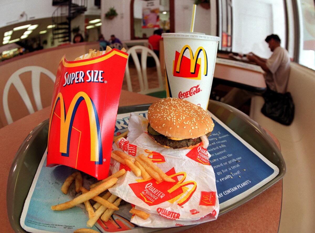 A Quarter Pounder with cheese, fries and a soda at a McDonald's restaurant.