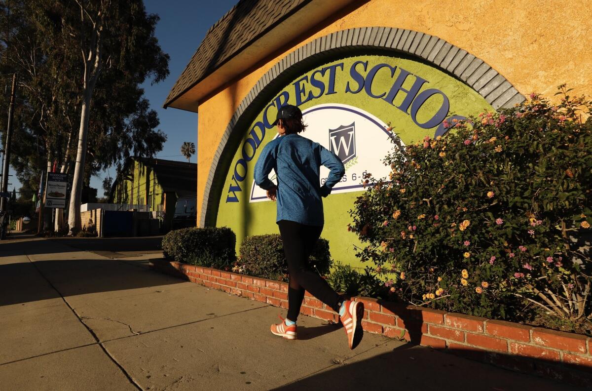 A jogger passes Woodcrest School in Tarzana Friday morning, which was closed due to a possible threat against the campus.