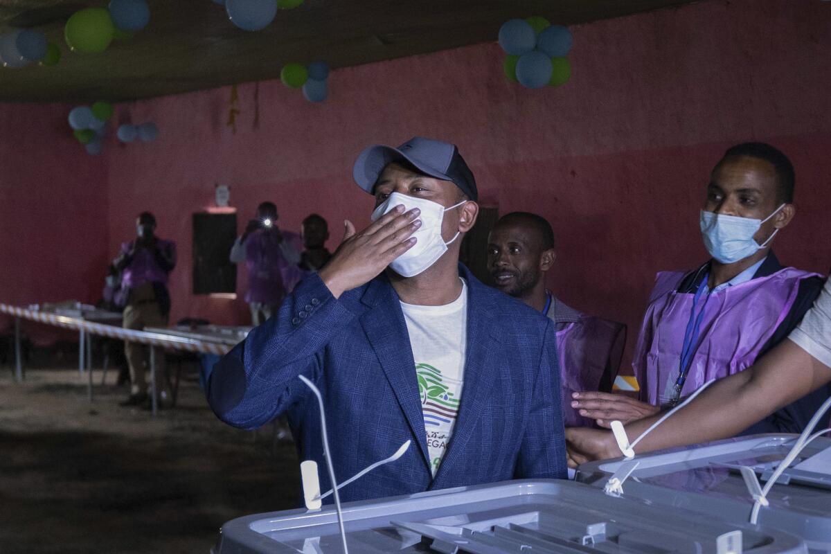 Abiy Ahmed holds his hand over his face mask at a polling place