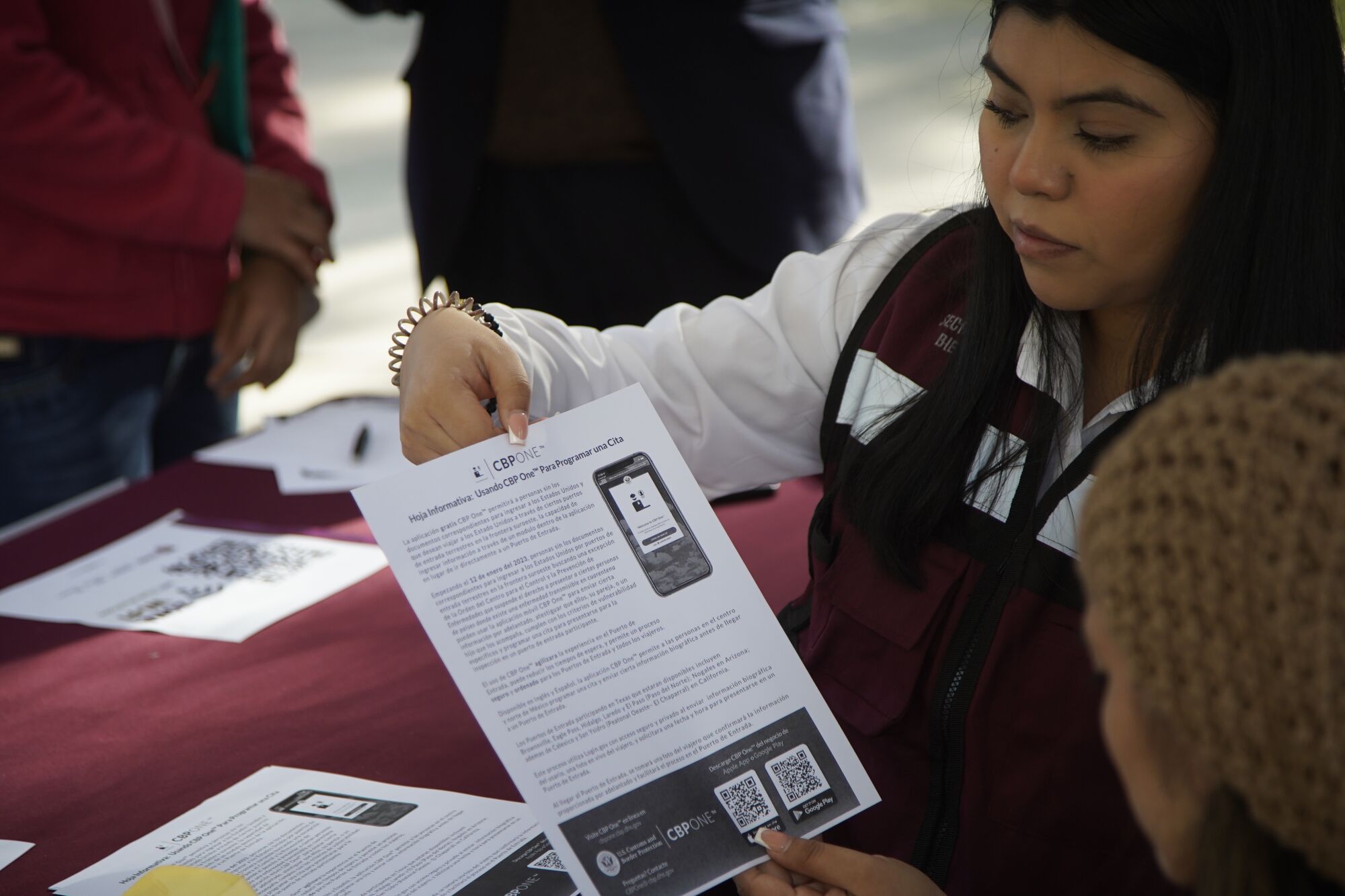 Un funcionario de Tijuana muestra información sobre la aplicación CBP One a una mujer de Michoacán.