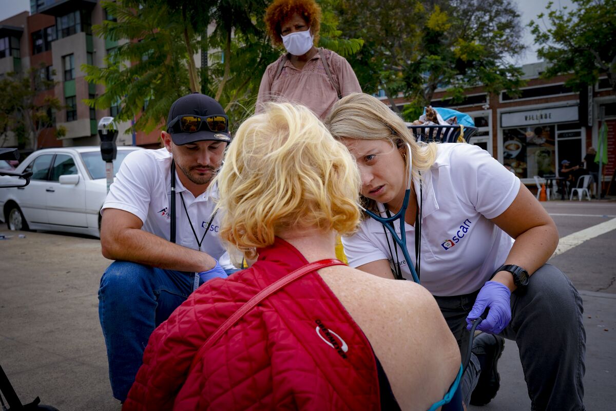 Gavin Goff and Laine Goettsch check on Betty McDaniel, a homeless woman they met on the street in downtown San Diego. 