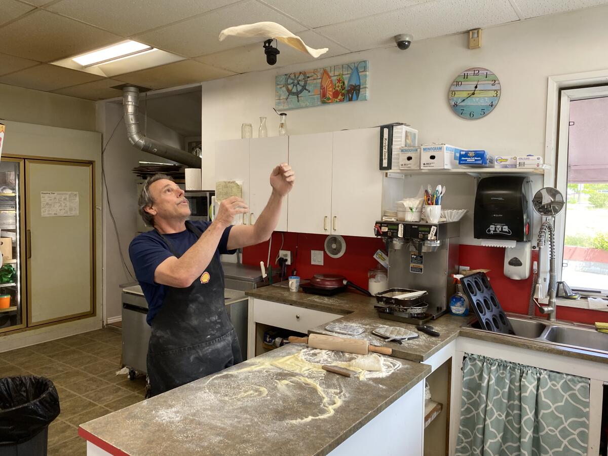 Chuck Laird, co-owner of a Shell station in Point Roberts, Wash., tosses a pizza for a customer.