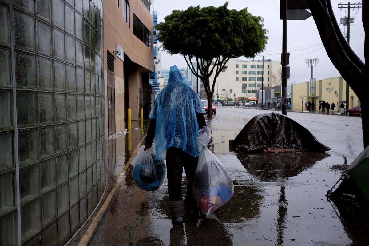 A homeless man on a rain-soaked sidewalk in Los Angeles