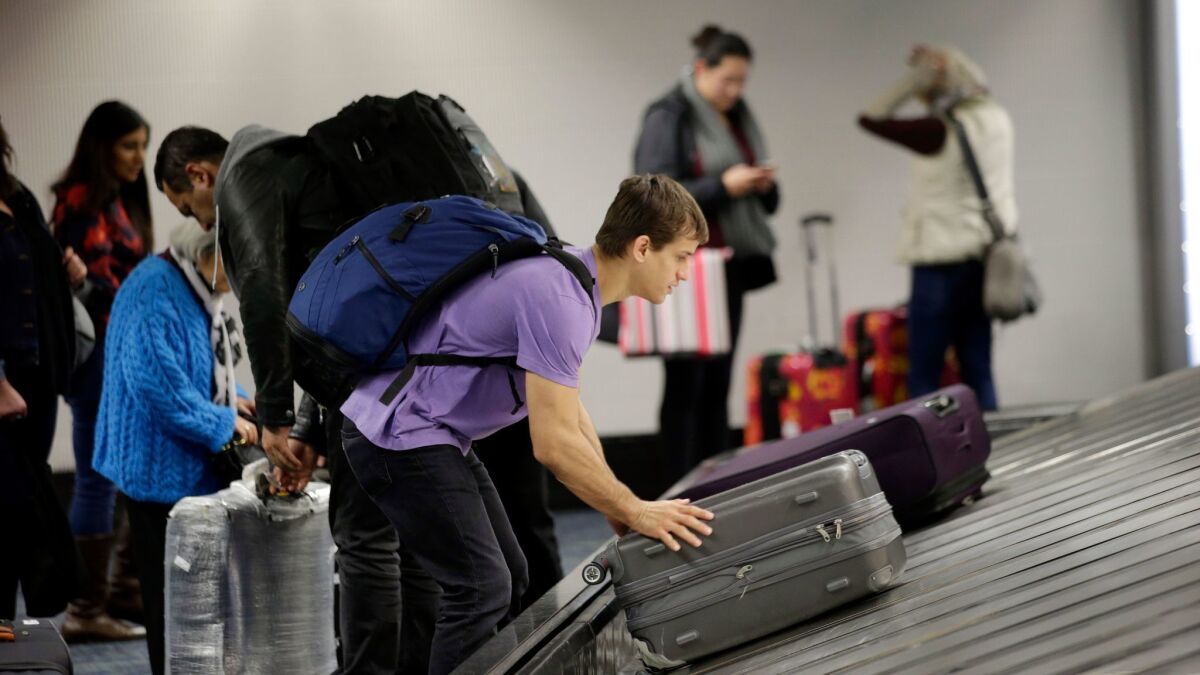 A traveler gathers his luggage at San Francisco International Airport. Fees for checked luggage are part of the $44.6 billion collected by the world's biggest airlines in 2016.