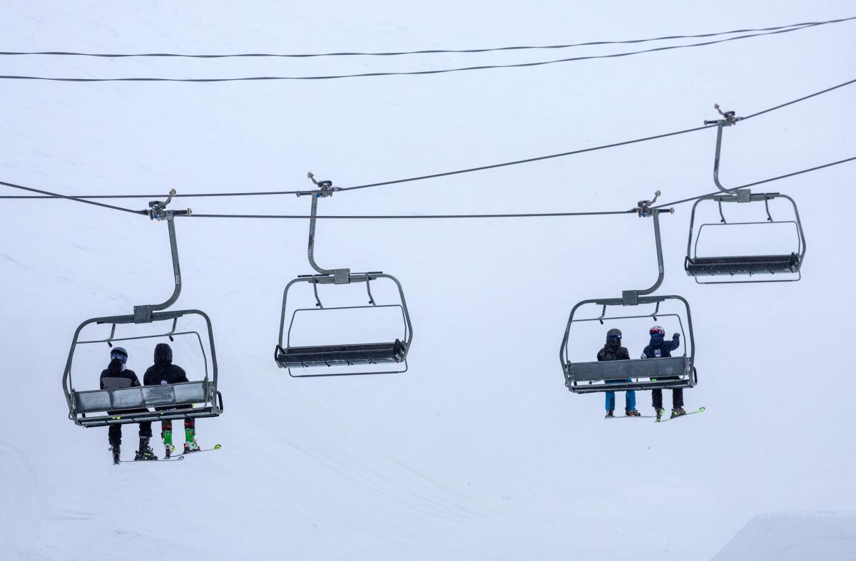 Skiers ride a chair lift on a blustery day at Mammoth Mountain.