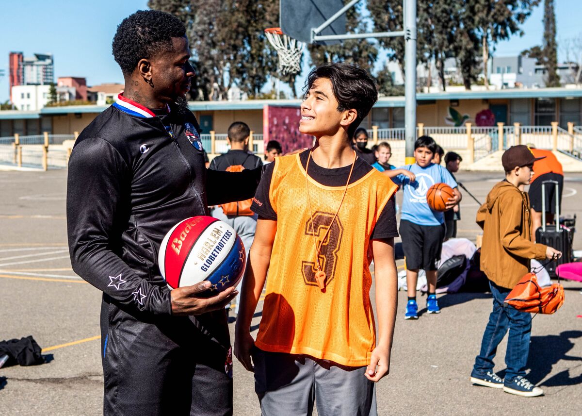 Arden Pala, 13, talks to Harlem Globetrotters player Saul 'Flip' White at Perkins K-8 School in Barrio Logan on Tuesday.
