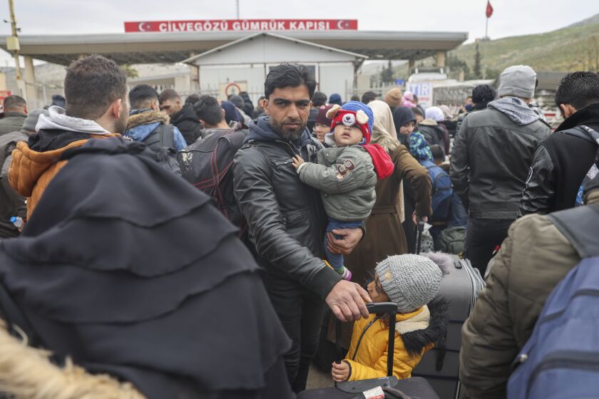 Sirios esperan para cruzar a Siria desde Turquía, en el paso fronterizo de Cilvegozu, cerca de la ciudad de Antioquía, en el sureste de Turquía, el 21 de febrero de 2023. (AP Foto/Unal Cam)
