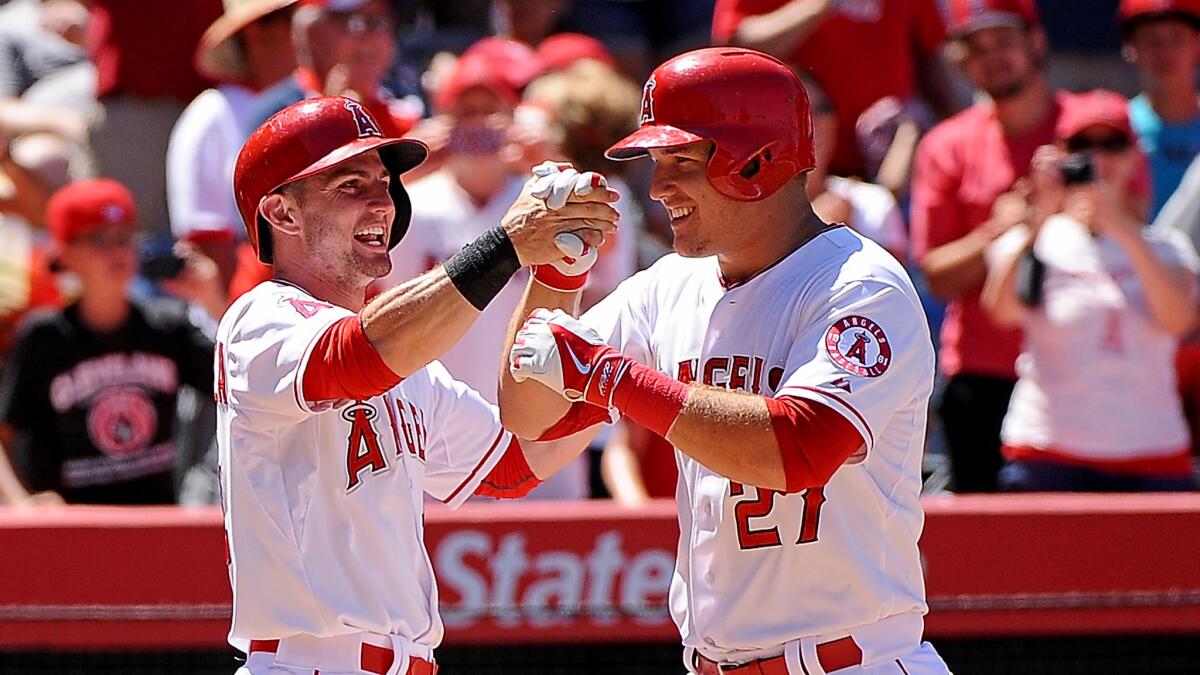 Angels center fielder Mike Trout is congratulated by second baseman Johnny Giavotella after hitting a grand slam against the Rangers in the sixth inning Sunday afternoon in Anaheim.