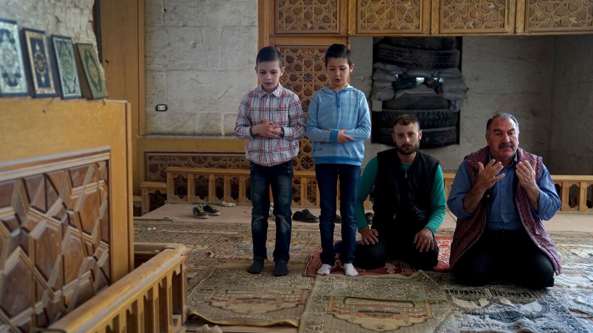 Abdullah Bayoud, right, a truck driver from Aleppo who was stunned by the damage at the Umayyad mosque, prays with his cousin Bilal Mansour. Two children unrelated to the men join them in prayer.