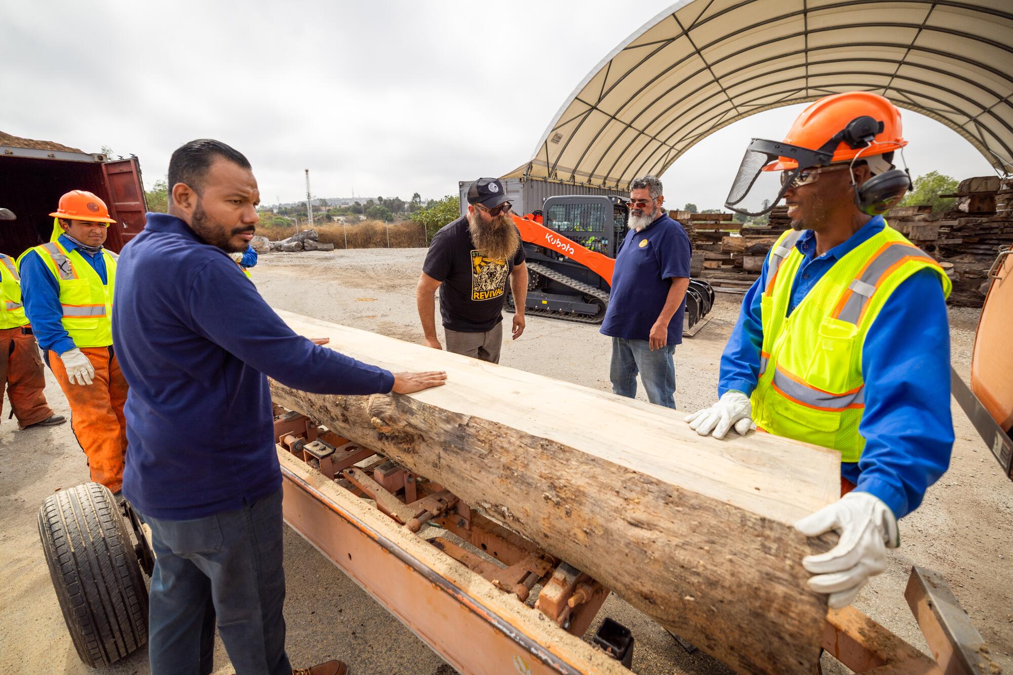 Workers stack freshly cut lumber.