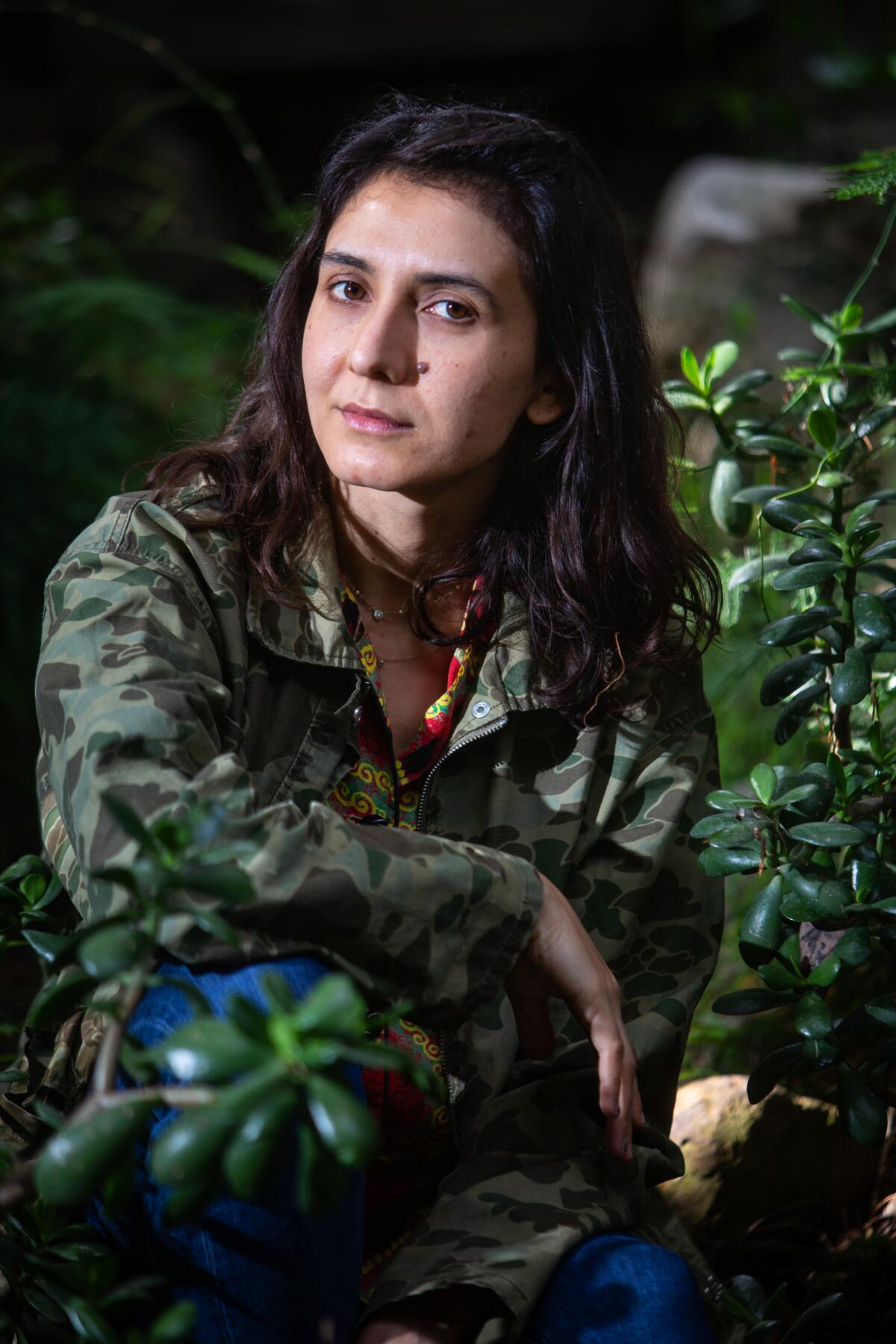 Author Ottessa Moshfegh poses crouched down outdoors near her home in Pasadena.