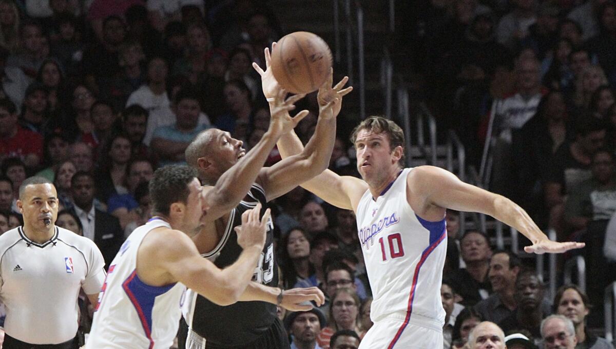 Spurs forward Boris Diaw drives between Clippers forwards Hedo Turkoglu, left, and Spencer Hawes (10) in the first half.