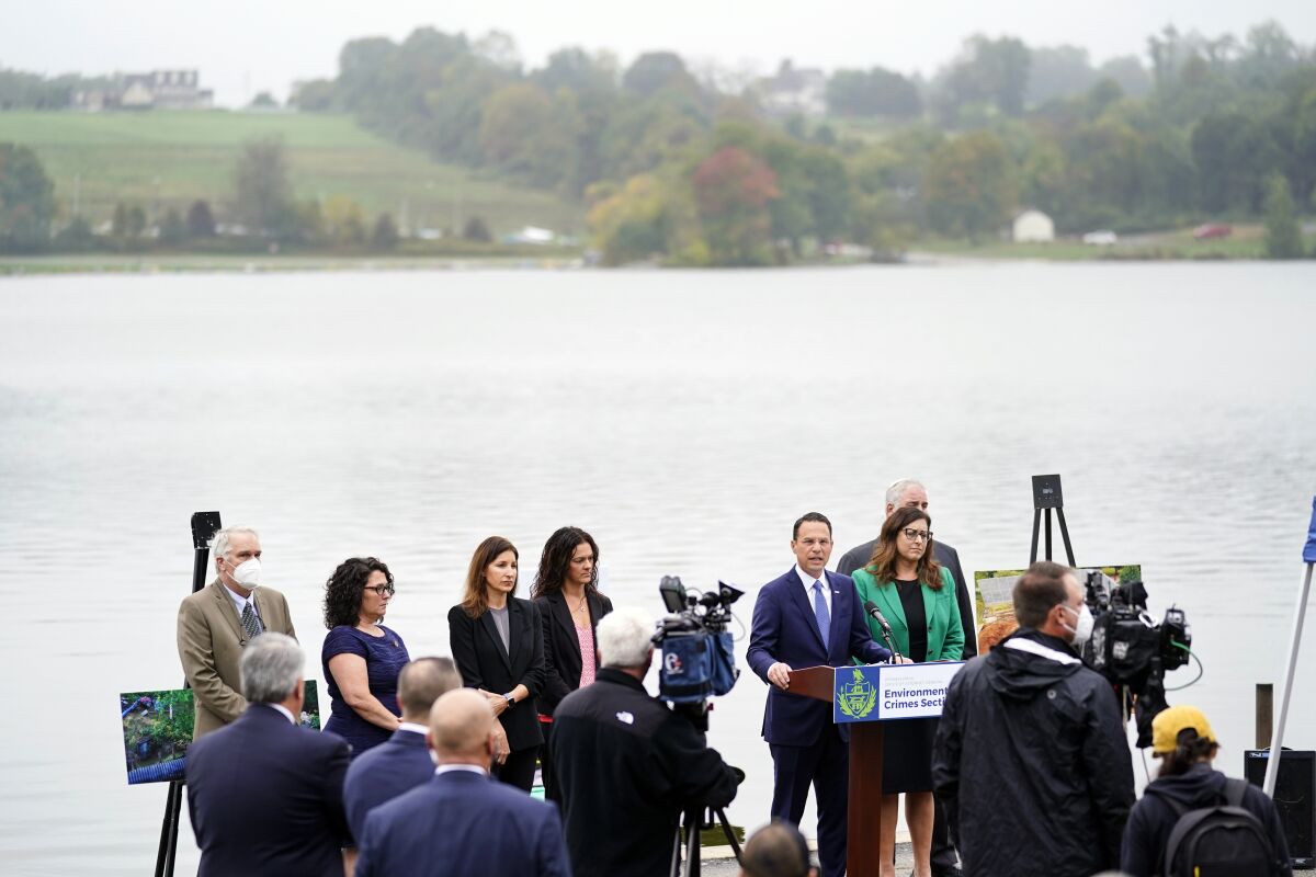 Pennsylvania Attorney General Josh Shapiro, at podium, speaks during a news conference at Marsh Creek State Park in Downingtown, Pa., Tuesday, Oct. 5, 2021. Shapiro filed criminal charges Tuesday against the developer of a problem-plagued pipeline that takes natural gas liquids from the Marcellus Shale gas field to an export terminal near Philadelphia. (AP Photo/Matt Rourke)