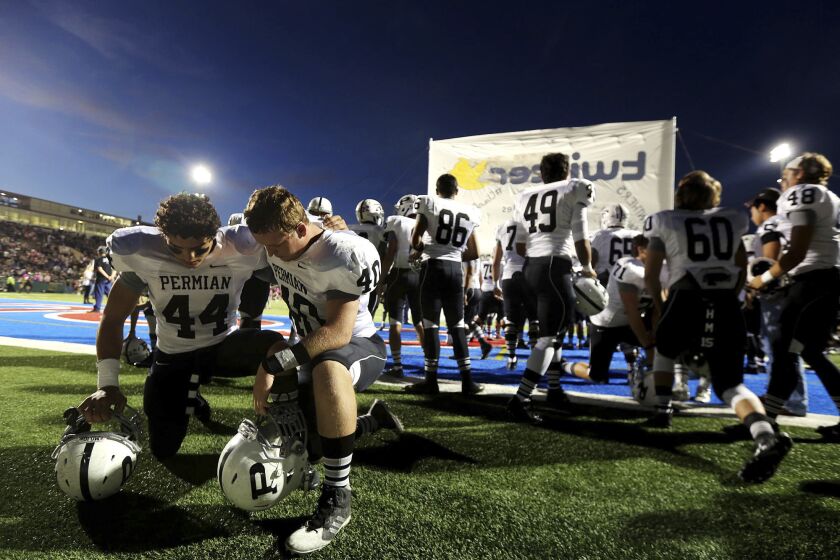 FILE - Permian linebacker Israel Martinez, left, and defensive lineman Tyler Tomlinson pray before a high school football game against Abilene on Friday, Oct. 17, 2014, at Shotwell Stadium in Abilene, Texas. Abilene won 30-13. A poll by The Associated Press and the NORC Center for Public Affairs Research conducted Sept. 9-12, 2022, finds that about 3 in 10 Americans say they feel God plays a role in determining which team goes home the victor. (Edyta Blaszczyk/Odessa American via AP, File)