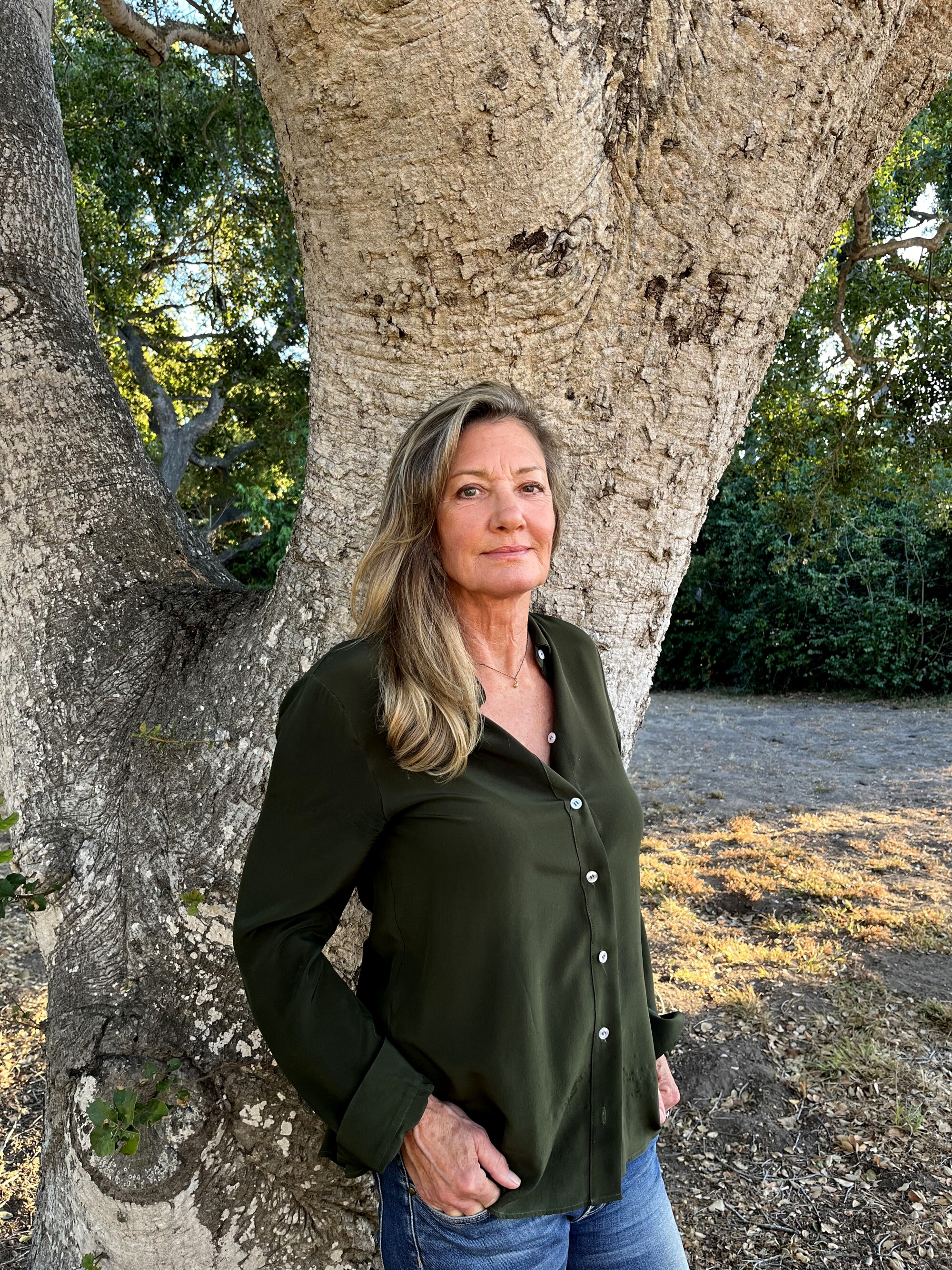 A woman stands in front of a tree 