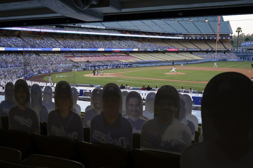 Cutouts of fans sit in the stands as Los Angeles Dodgers starting pitcher Clayton Kershaw, right, throws to Arizona Diamondbacks' Christian Walker during the first inning of a baseball game Thursday, Sept. 3, 2020, in Los Angeles. (AP Photo/Marcio Jose Sanchez)