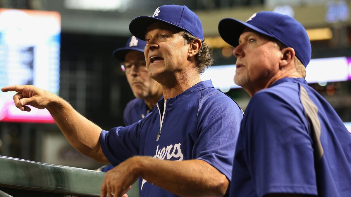 Dodgers Manager Don Mattingly, left, and hitting coach Mark McGwire wait for an instant replay review during a game against the Arizona Diamondbacks.
