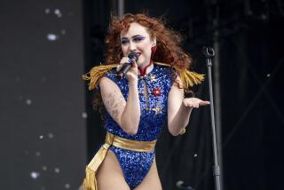 Chappell Roan singing into a mic wearing blue sequinted leotard. 