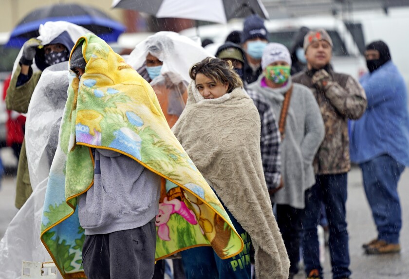 People bundled in blankets line up in Houston. 