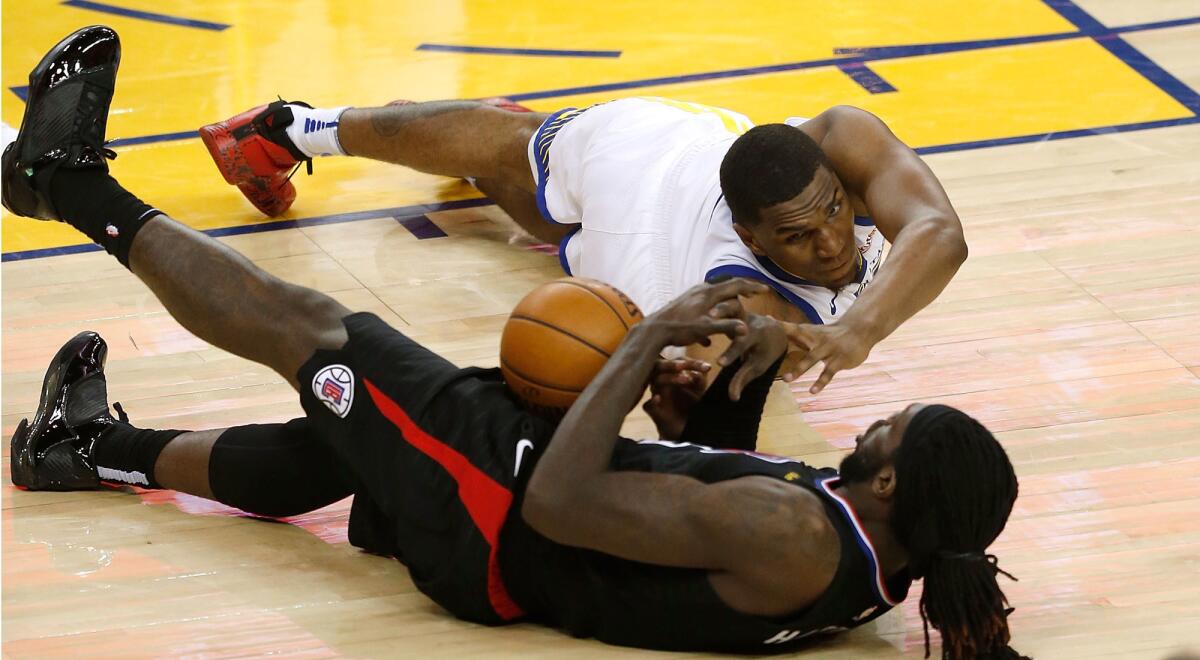 Clippers forward Montrezl Harrell tries to collect a loose ball against Warriors forward Kevon Looney during Game 1 on Saturday.
