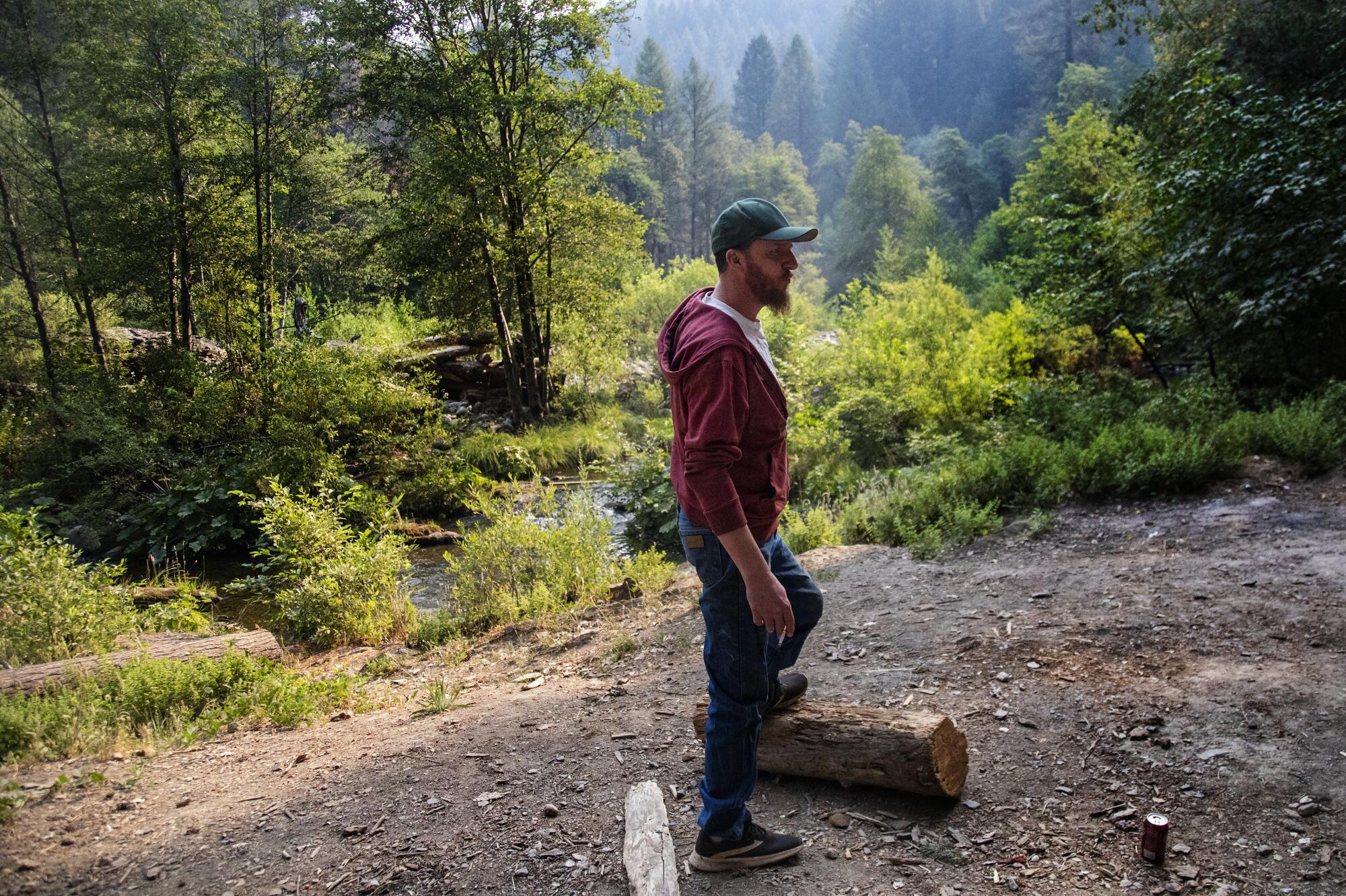  Jedediah Anderson stands with his foot on a log at a wilderness campsite.