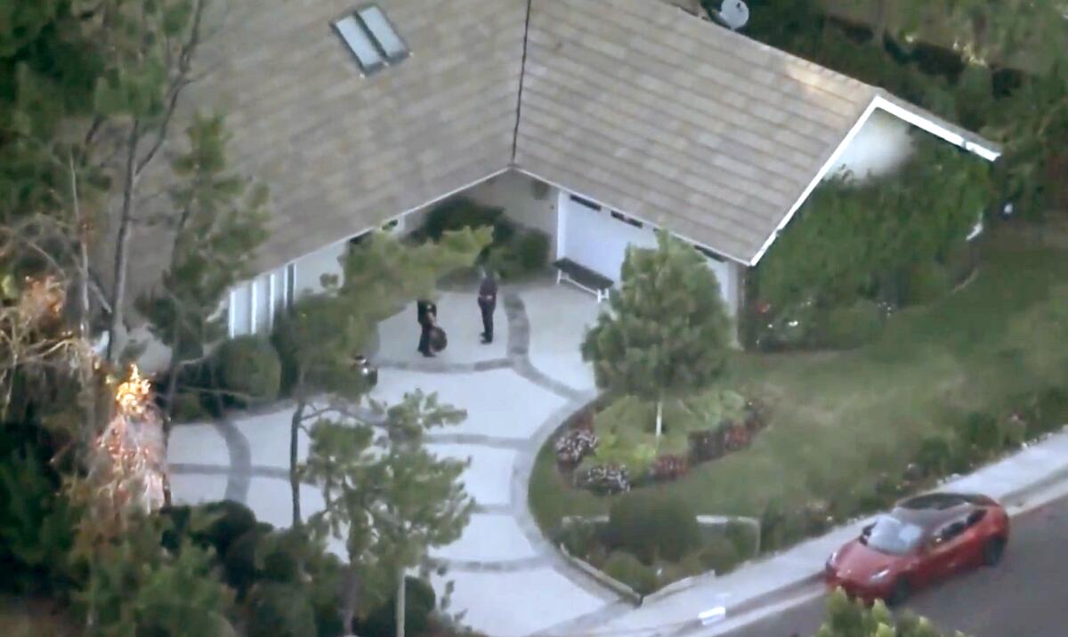 Police stand outside a home in Tarzana.