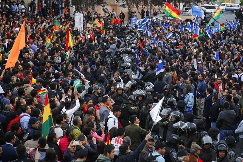 Police on Monday stand between supporters of opposition presidential candidate Carlos Mesa, left, and supporters of Bolivian President Evo Morales outside the Supreme Electoral Court in La Paz, where election ballots are being counted.