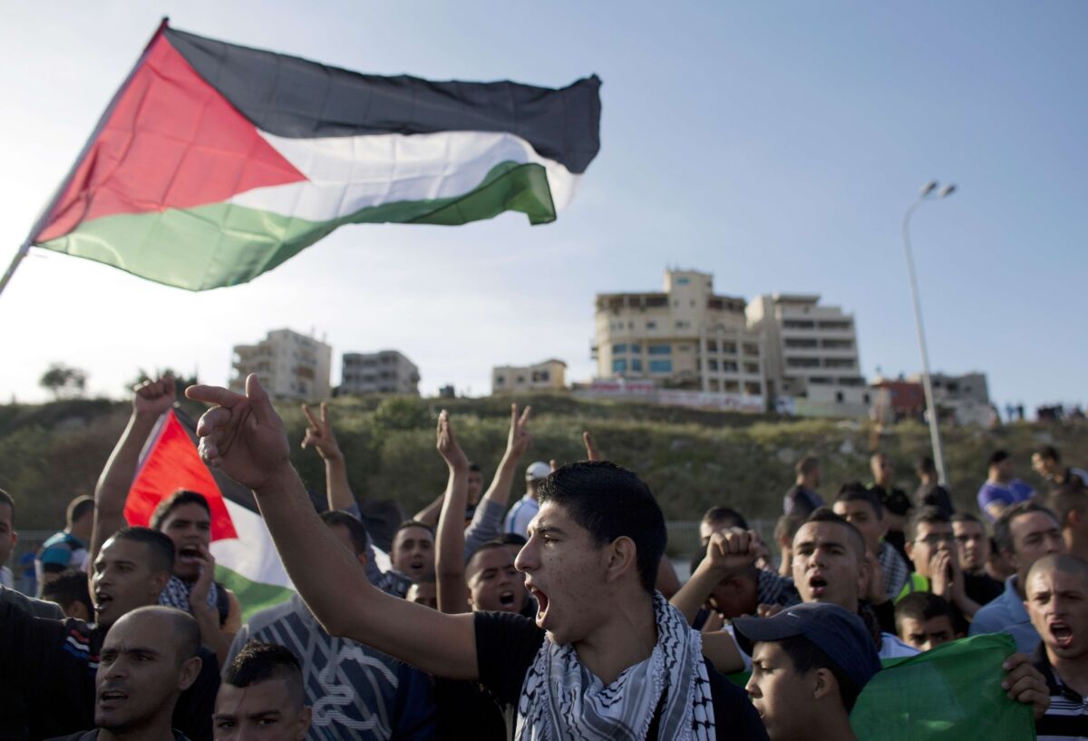 Israeli Arabs in Umm al-Faham hold Palestinian flags shouting slogans during a protest last week against an act of vandalism at the city's mosque.