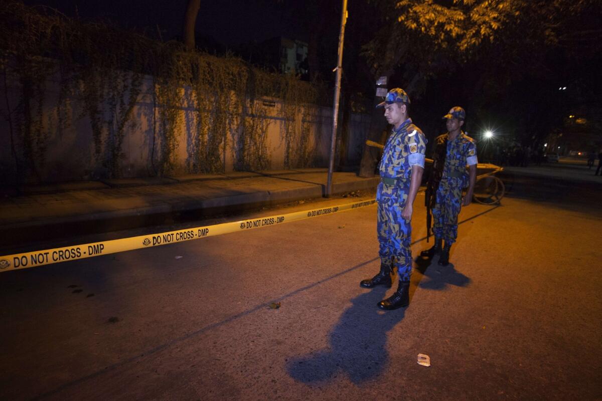 Bangladeshi police officers stand guard at the site where an Italian charity worker was fatally shot in Dhaka.
