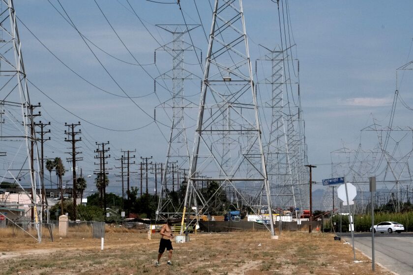 A jogger runs in extreme heat under high tension electrical lines in the North Hollywood section of Los Angeles on Saturday, Aug. 15, 2020. California has ordered rolling power outages for the first time since 2001 as a statewide heat wave strained its electrical system. (AP Photo/Richard Vogel)