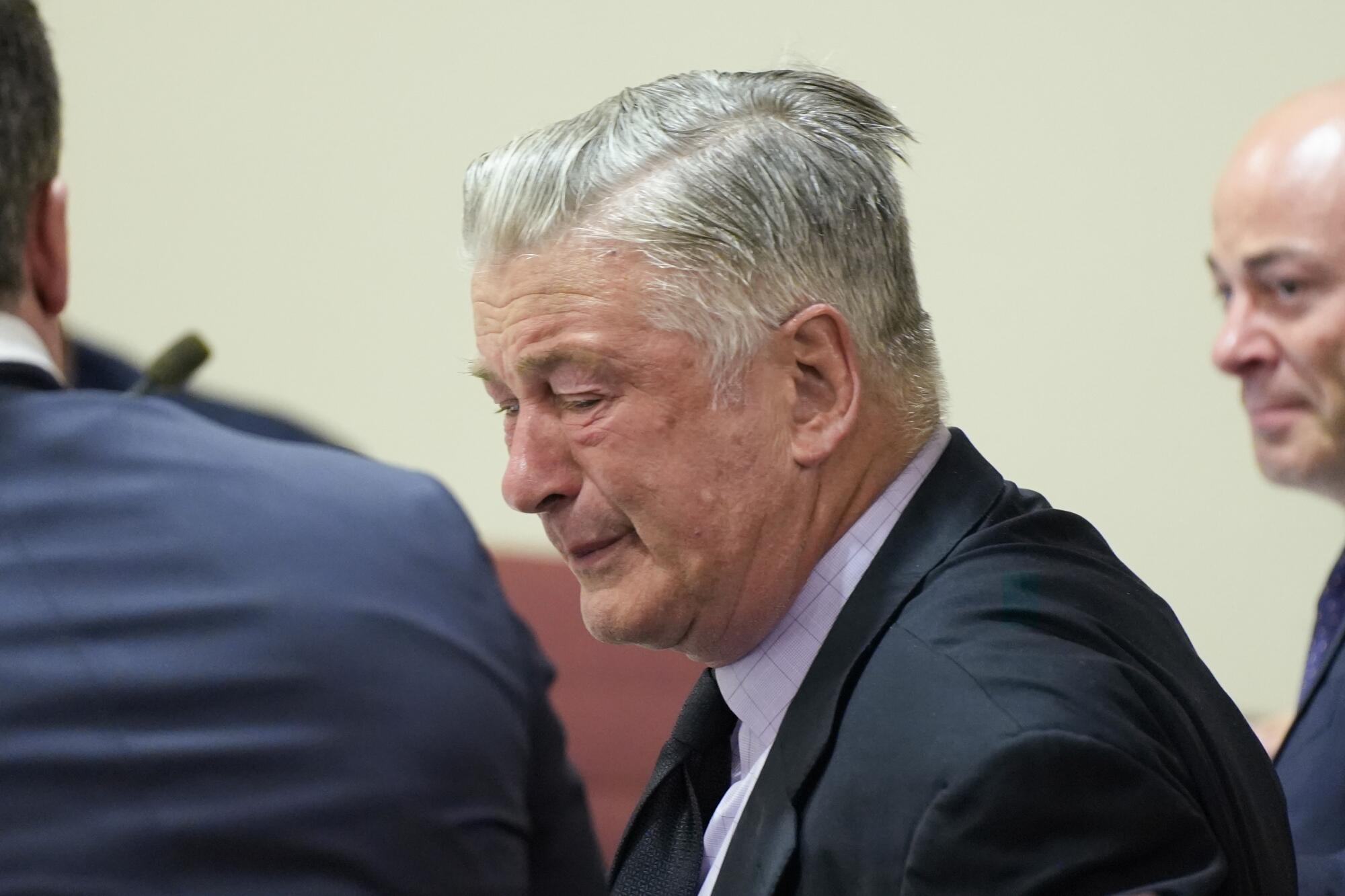 Actor Alec Baldwin closes his eyes as he sits between his attorneys. 