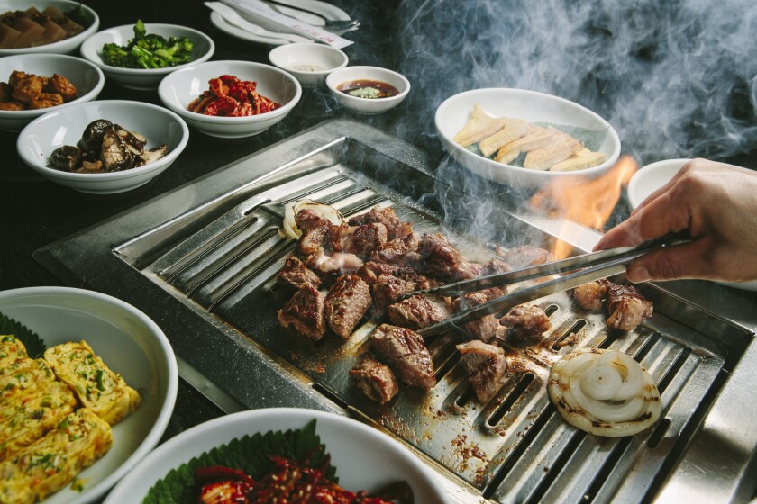Ribeye steak grills at a table with a variety of banchan at Park’s BBQ.