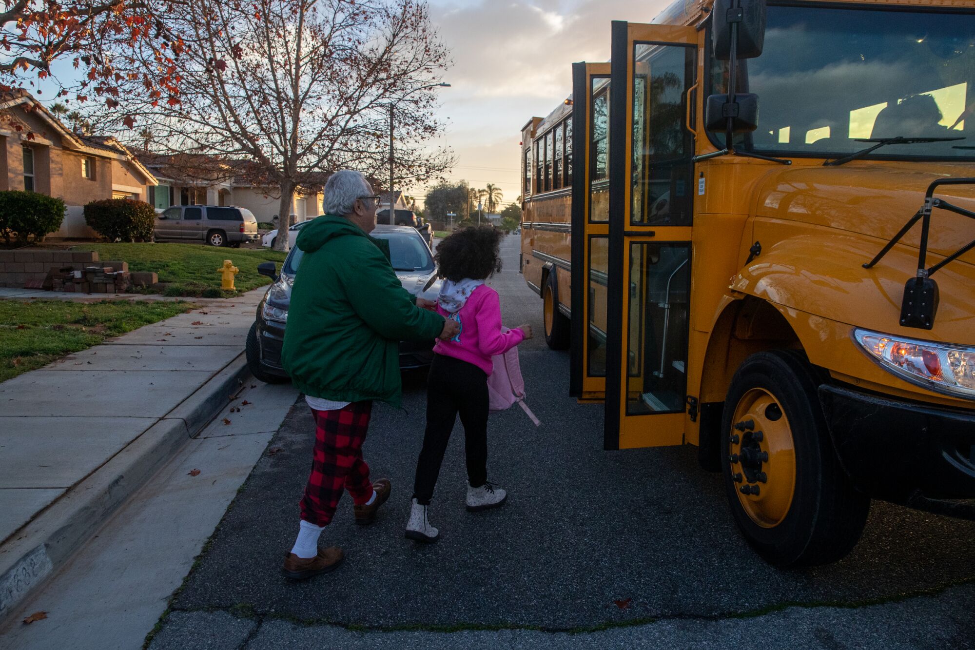 A man helps a girl onto a school bus