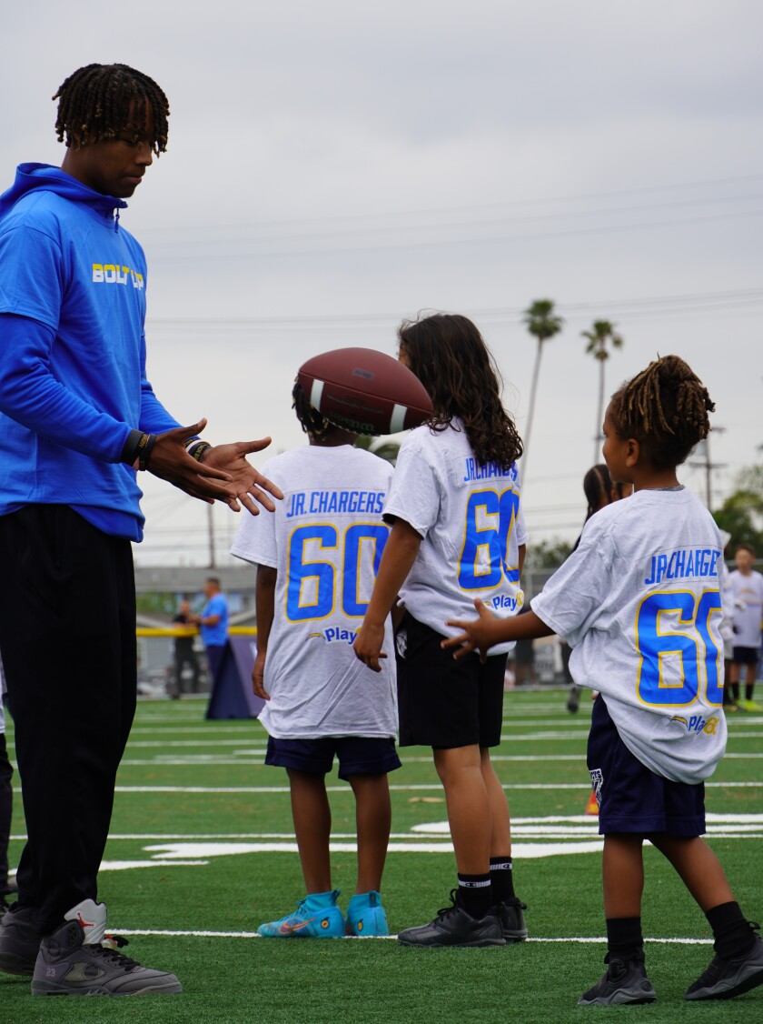 Devin Kirkwood lance un ballon de football avec des enfants.