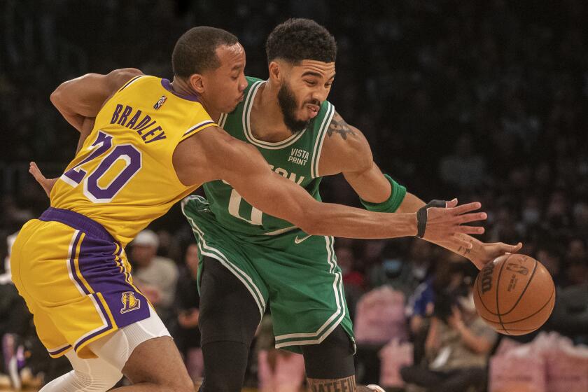 LOS ANGELES, CA - December 07 2021: Los Angeles Lakers guard Avery Bradley (20) reaches in on Boston Celtics forward Jayson Tatum (0) in first half as the Los Angeles Lakers takes on the Boston Celtics at Staples Center on Tuesday, Dec. 7, 2021 in Los Angeles, CA. (Brian van der Brug / Los Angeles Times