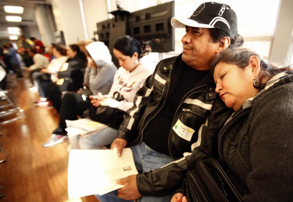 Berta Martinez naps on the shoulder of her husband, Marco Letona, as they wait more than two hours to see an enrollment counselor in Los Angeles. Monday is the deadline to begin an application for health insurance under the Affordable Care Act.
