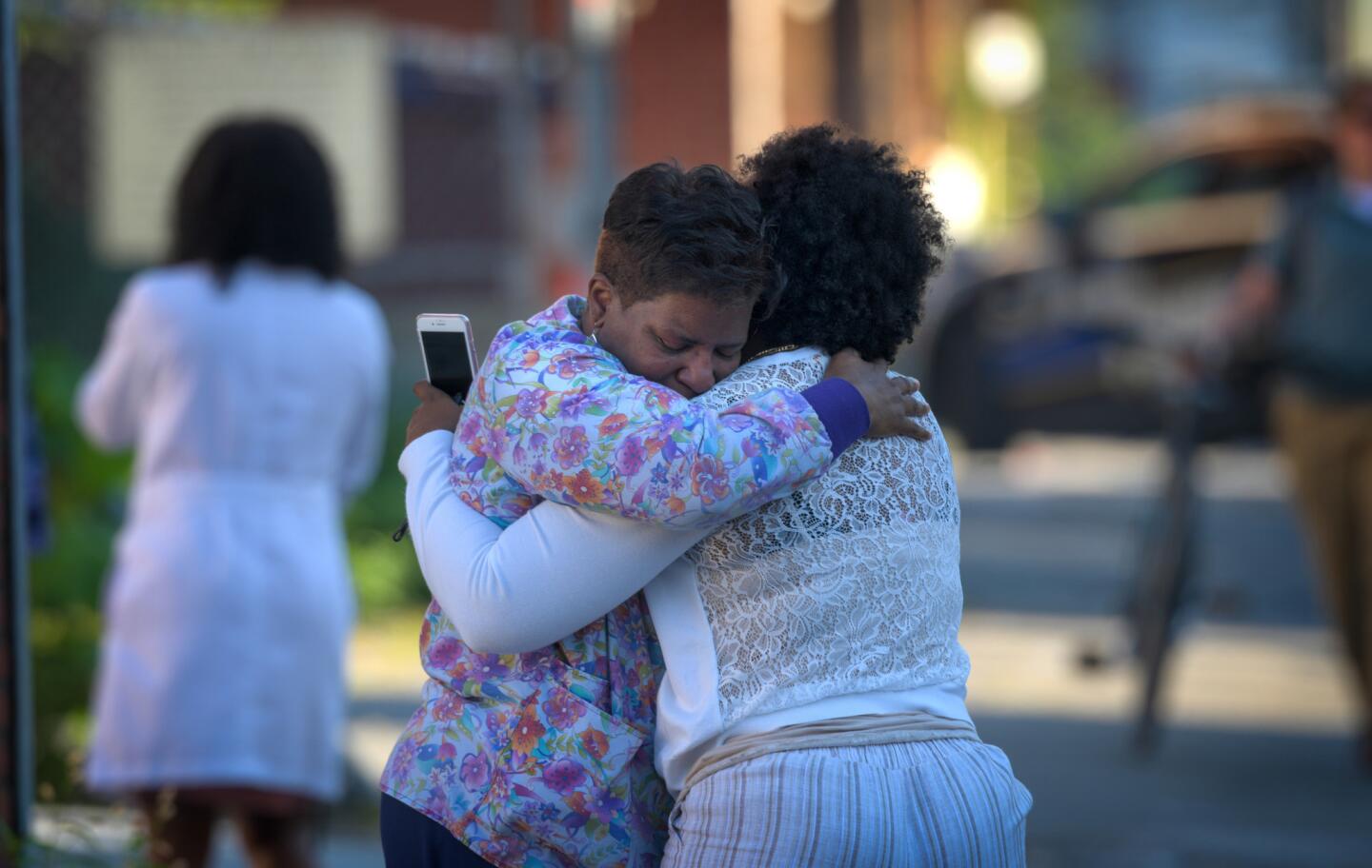Two women embrace in an alley behind the Man Alive drug treatment center on Maryland Avenue shortly after a shooting. Baltimore police say an officer and at least one other person, the suspect, were shot at the center.