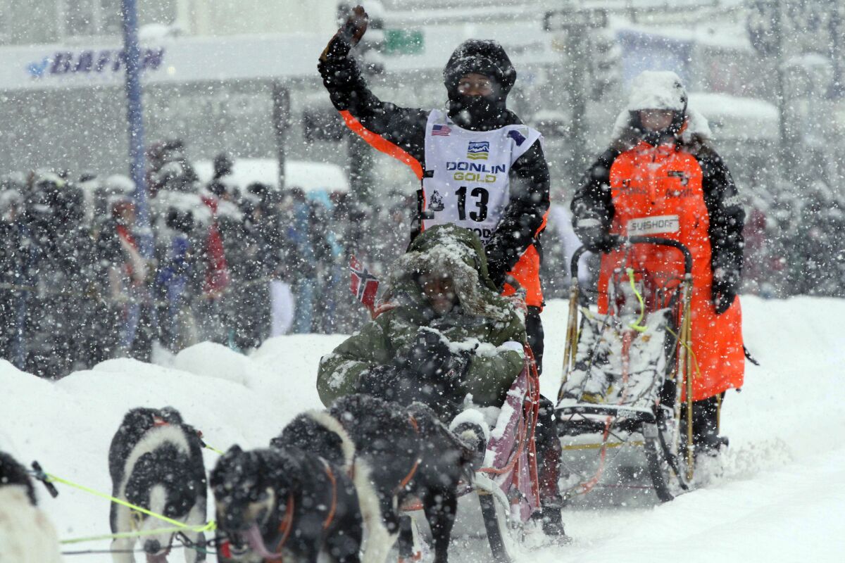 Hanna Lyrek, a musher from Alta, Norway, waves to fans while taking her sled dogs through a snowstorm in downtown Anchorage, Alaska, on Saturday, March 5, 2022, during the ceremonial start of the Iditarod Trail Sled Dog Race. The competitive start of the nearly 1,000-mile race will be held March 6, 2022, in Willow, Alaska, with the winner expected in the Bering Sea coastal town of Nome about nine days later. (AP Photo/Mark Thiessen)