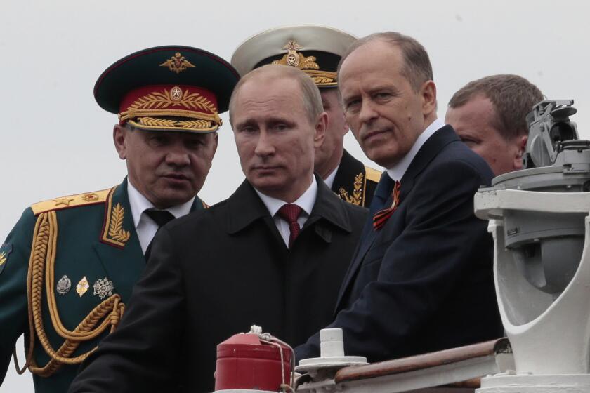 Russian President Vladimir Putin, flanked by Defense Minister Sergei Shoigu, left, and FSB Chief Alexander Bortnikov, arrives on a boat in May 2014 after inspecting battleships during a navy parade marking Victory Day in Sevastopol, Crimea.