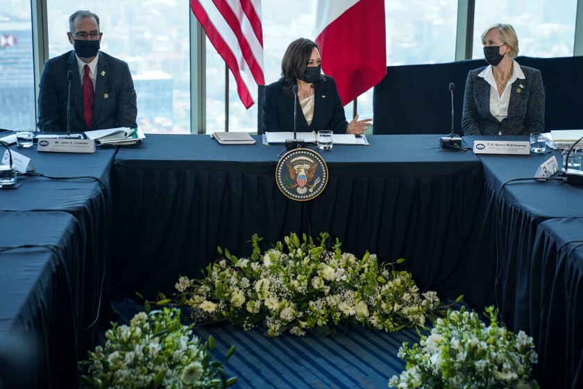 Kamala Harris sitzt an einem Tisch, flankiert von zwei Beratern.