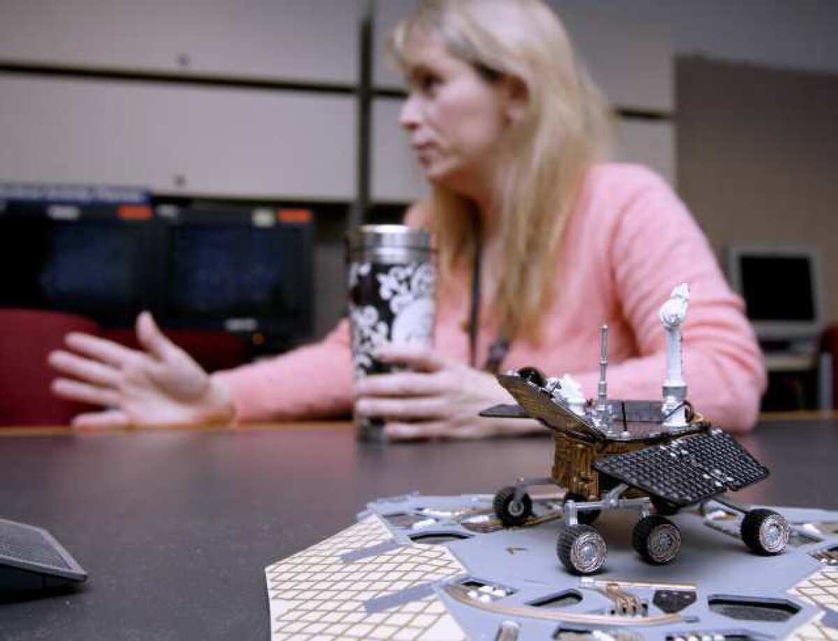 With a miniature model in the foreground, Jet Propulsion Laboratory Mars rover driver Ashley Stroupe, talks about the rover Opportunity.