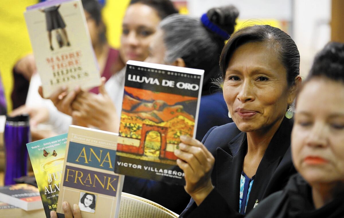 Cleotilde Flores, center, holds her favorite books that she has read with other mothers at the Bravo Medical Magnet High School literature club.