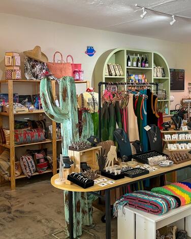 A clothing store with other items including a large metal cactus and display tables