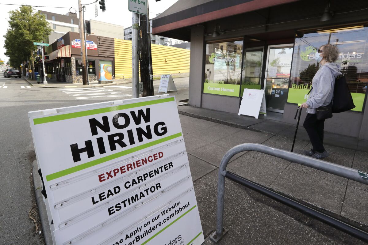 A pedestrian walks past a board advertising job openings in Seattle.