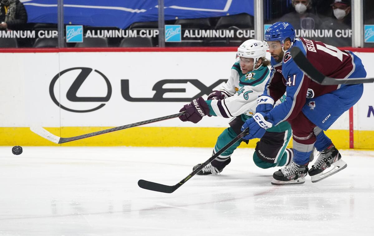 Ducks center Trevor Zegras reaches out for the puck as Colorado Avalanche center Pierre-Edouard Bellemare defends.